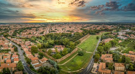 Aerial sunset panorama of the bastions and medieval wall of the center of Ferrara Italy with stunning yellow, blue sky colors - obrazy, fototapety, plakaty