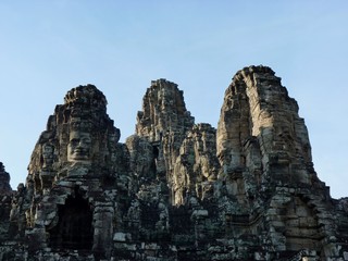 Ruins of Angkor, face towers of Bayon temple against blue sky, Angkor Wat, Cambodia
