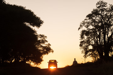 Silueta de auto frente a una puesta de sol