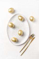 Easter table setting with  golden eggs on white table. Top view.