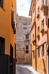 Girona, Spain, August 2018. A fragment of a medieval building at the end of a narrow city street.