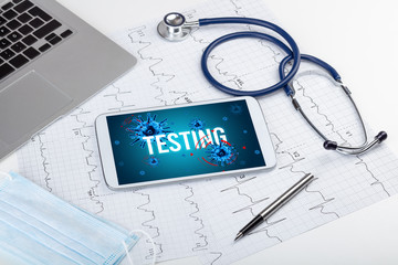 Tablet pc and doctor tools on white surface with TESTING inscription, pandemic concept