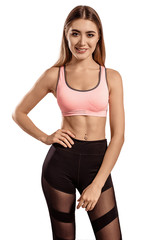Obraz premium Beautiful young woman in sportswear standing on a white isolated background. Tightened, thin body. Fitness model. Pose.