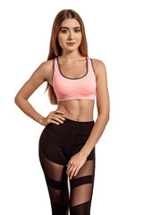 Obraz premium Beautiful young woman in sportswear standing on a white isolated background. Tightened, thin body. Fitness model. Pose.