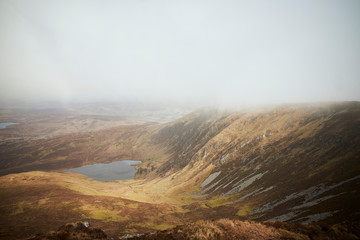 lago entre montañas, pendiente en un dia nublado. comienzo de una reja, alambrado rustico en el medio de la montaña. Donegal. Slieve leave. Irlanda