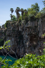steep cliff above the mediterranean sea, palm trees grow on steep cliff of turkey