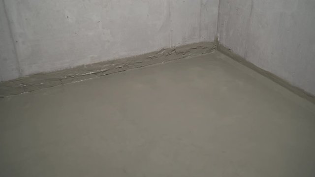 A worker is waterproofing a concrete floor. Construction mix waterproofing. Concrete floor with fresh construction waterproofing.