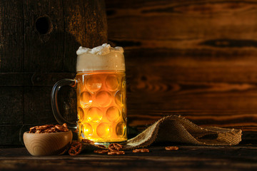 Large beer in glass with wooden barrel on the wood background.