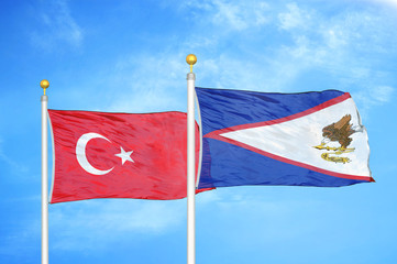 Turkey and American Samoa two flags on flagpoles and blue cloudy sky