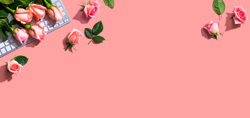 Obraz na płótnie Canvas Computer keyboard with pink roses - flat lay