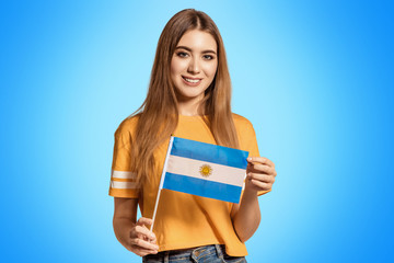 A beautiful young woman holds in her hands the flag of Argentina. Exchange student, learn language....
