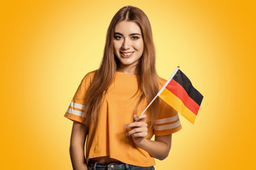 A beautiful young woman holds in her hands the flag of Germany. Exchange student, learn Germanic language. Tourist traveling. Football fan.
