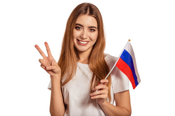 A beautiful young woman holds in her hands the flag of Russia and shows the sign Victoria, Peace,...