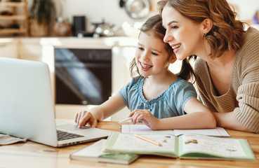 Happy girl with mother studying online at home.