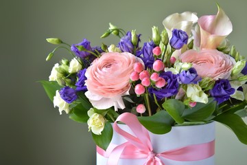 Amazing tender bouquet with pink ranunculus, violet Alstroemeria flowers and tiny white roses in cardboard box with pink ribbon. Beautiful bunch of spring flowers. Easter gift. Seasonal spring flowers