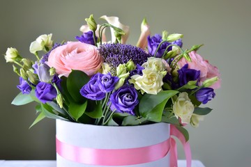 Amazing tender bouquet with pink ranunculus, violet Alstroemeria flowers and tiny white roses in cardboard box with pink ribbon. Beautiful bunch of spring flowers. Easter gift. Seasonal spring flowers