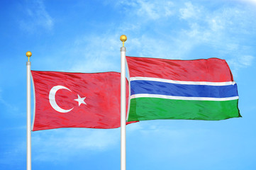 Turkey and Gambia two flags on flagpoles and blue cloudy sky