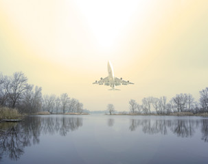A plane over a dark lake flies up in the sky to the sun