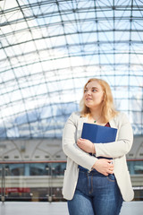 blonde girl in a jacket stands with a folder in a business center body positive