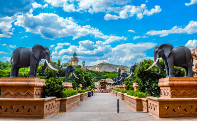 Entrance of The Palace / Lost City /Sun City with stone statues under blue and cloudy sky