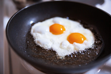 Two eggs fried in a pan with oil