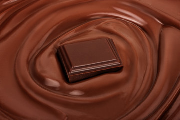 Swirl of melted chocolate with piece of chocolate bar.