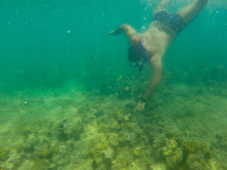 rapaz em mergulho de snorkel no mar com recife de corais