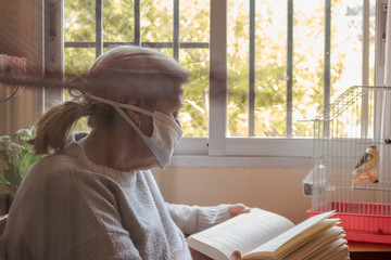 Mujer leyendo un libro en su casa mientras pasa la cuarentena