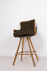 green bar stool with soft upholstery and gold legs on a white background