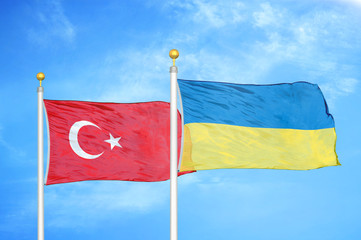 Turkey and Ukraine two flags on flagpoles and blue cloudy sky