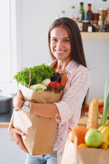 Young woman holding grocery shopping bag with vegetables. Young woman