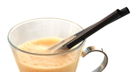 Foam on iced coffee in glass with silver handle and two black straws on white, selective focus