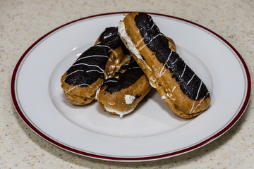 Freshly baked eclairs on a white plate