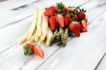 White and green asparagus with strawberries on rustic background