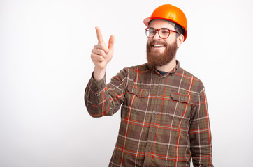 Young bearded builder engineer or architect is pointing forward on white background.