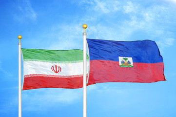 Iran and Haiti two flags on flagpoles and blue cloudy sky