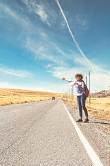 Fototapeta na wymiar Beautiful woman hitchhiking on road in forest, hitchhiking with thumbs up in a countryside road, Travelling and hitchhiking concept.