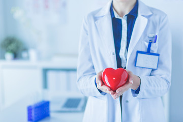 A doctor with stethoscope examining red heart, isolated on white background