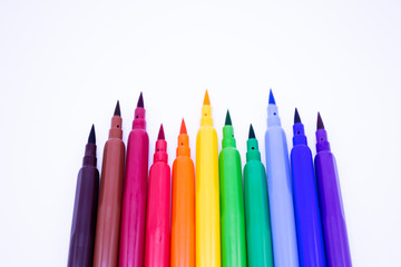 Multi-colored markers with a brush tip, arranged according to the colors of the rainbow. White background. The concept of creativity, drawing, bright world, back to school, study. Copy space