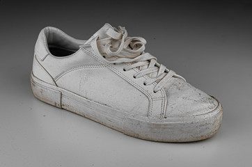 Dirty, used, muddy white right shoes on white dirty floor