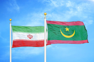 Iran and Mauritania two flags on flagpoles and blue cloudy sky