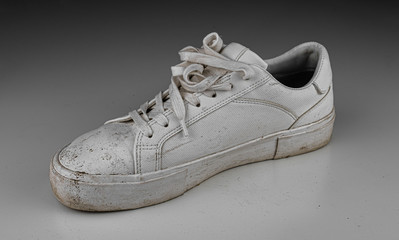 Dirty, used, muddy white right shoes on white dirty floor