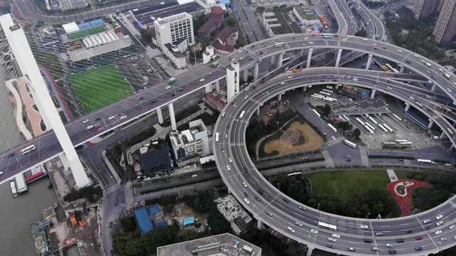 Panning aerial shot of Nanpu bridge ring-shaped interchange, interesting elevated road construction. Camera slowly turn right, reveal large circular junction. Part of inner ring road of Shanghai city