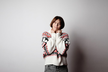 Young happy hipster girl posing in the studio wearing trendy clothing.