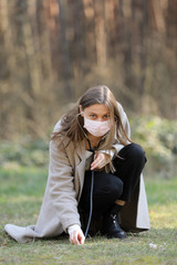 young woman in protective mask listening to the ground with stethoscope in the park. selective focus. copy space