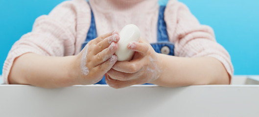 Hand hygiene concept. Female hands are holding antibacterial soap with foam on a blue background. Hand antiseptic during the coronovirus pandemic