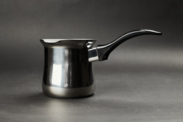 silver coffee turk pot with black handle on a black background. turkish coffee maker.