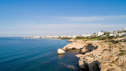 Fototapeta premium Aerial bird's eye view of coastline landmark ‘Love bridge’ and sea caves at Cavo Greco, Ayia Napa, Famagusta, Cyprus from above. A tourist attraction cliff rock natural formation arch in Ammochostos.