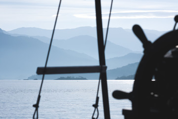 View of the mountains of the south coast of Rio de Janeiro with a defocused sailboat tiller in the foreground.
