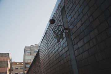 basketball hoop against blue sky and brick wall
